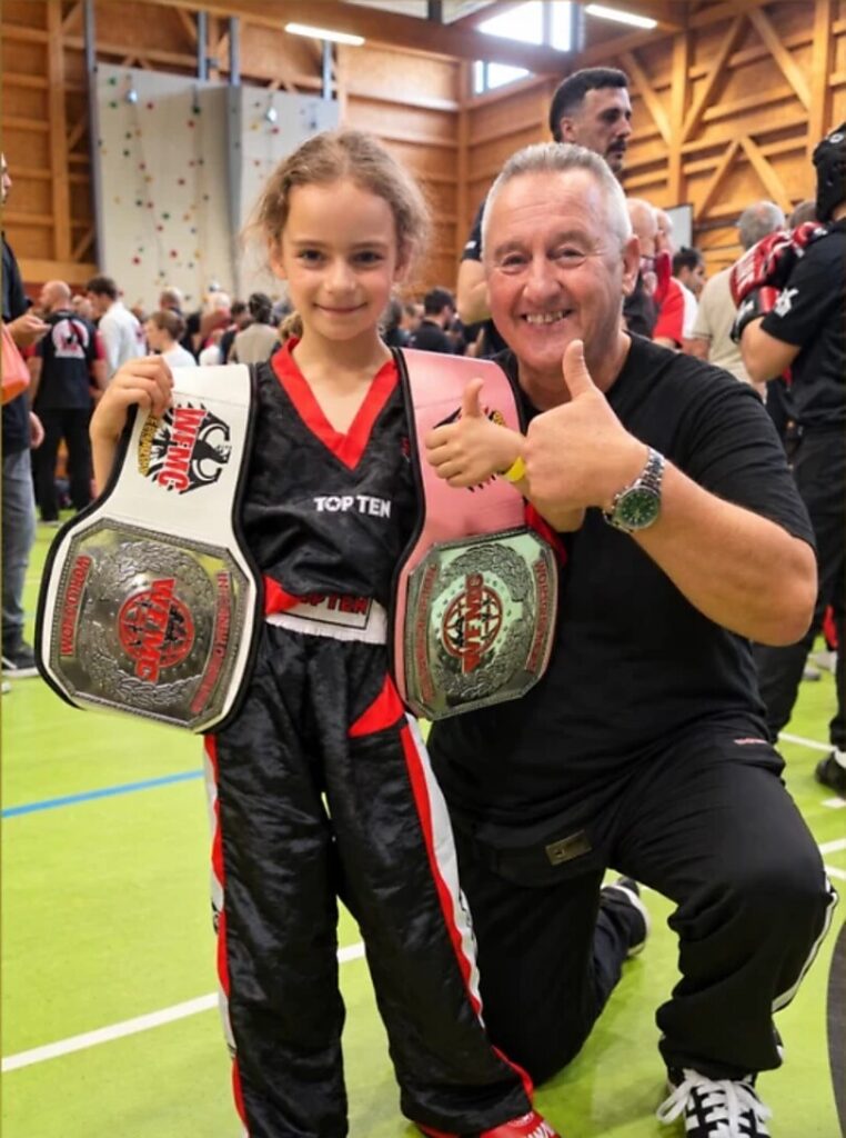 Schülerin der Westwood Kampfsport Akademie mit zwei Titelgürteln und Trainer Saly Brenke